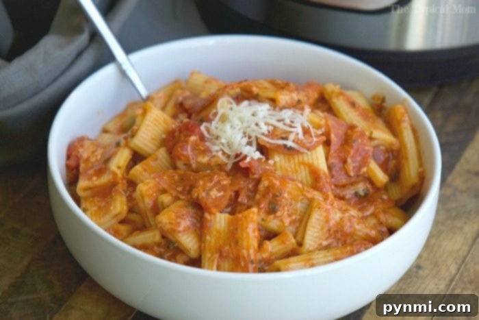Instant Pot pizza pasta is great! Super easy to dump it all in your pressure cooker and put in all of your favorite pizza toppings. A fun dinner recipe with a fun pizza twist that tastes even better the next day, if you have leftovers that is! #instantpot #pizza #pasta #dinner #instantpotrecipes #thetypicalmom #pizzapasta Instant Pot pizza pasta served in a bowl, garnished with fresh basil, next to the pressure cooker, symbolizing a quick and delicious family meal.