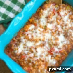 Baked stuffed pepper casserole with melted cheese, ground meat, rice, and vegetables in a turquoise dish.