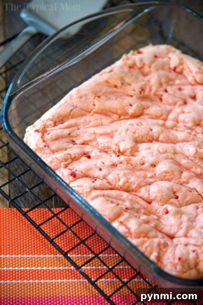 Make brownies out of cake mix easily with just 2 ingredients and any flavor of cake mix you like! Rich and chewy strawberry brownies are our favorite but try lemon cake mix brownies too. A quick dessert your kids will love and cheap to make for a bunch of people #cakemix #brownies #strawberry #lemon #cakemixbrownies Vibrant strawberry brownie batter fills a glass baking dish, sitting on a cooling rack atop an orange placemat. This simple visual hints at a surprising twist on a classic treat: easily make rich, flavorful brownies from a cake mix.