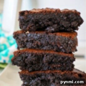 Turn Cake Mix into Perfect Brownies 3 A stack of four gooey chocolate brownies made from cake mix sits enticingly on a white plate, set against a blurred turquoise background.