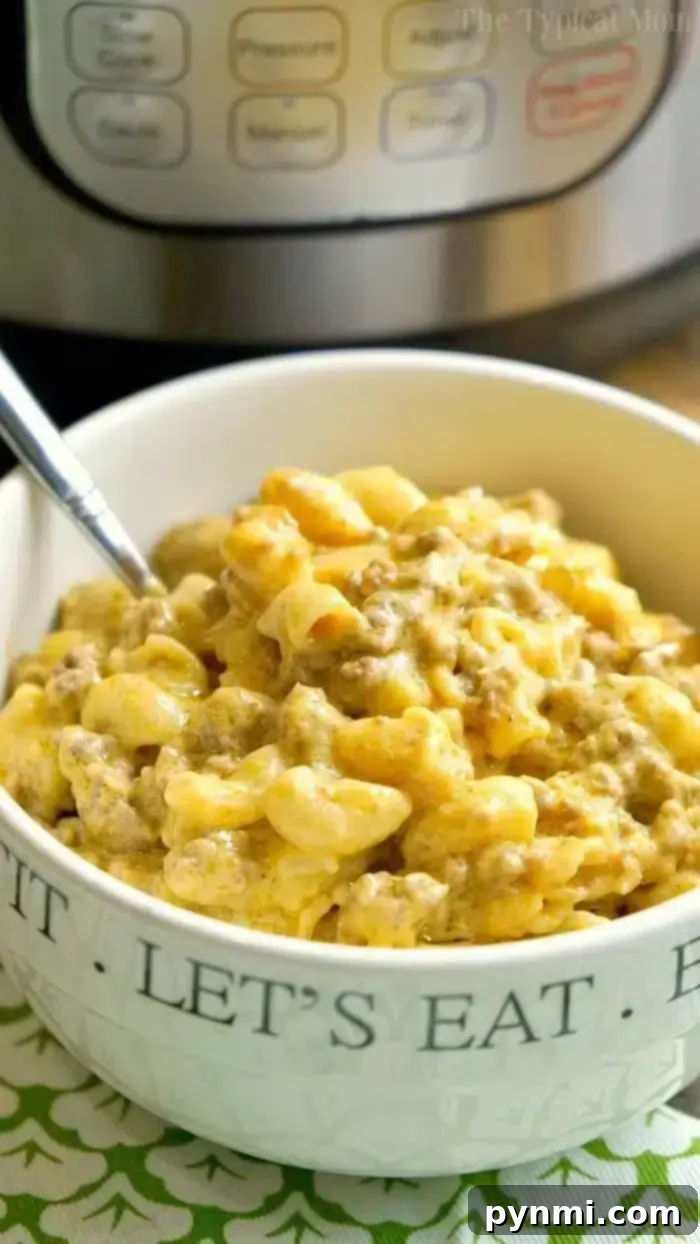 A large serving spoon scooping Instant Pot Cheeseburger Mac and Cheese from the pot, highlighting its creamy, rich texture and abundant ground beef.