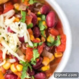A bowl of taco soup with kidney beans, corn, tomatoes, and cilantro topped with shredded cheese captures the essence of an easy instant pot taco soup recipe.
