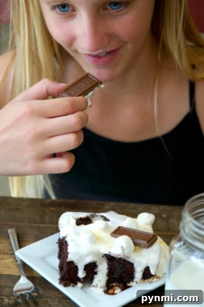 Close-up of a S'mores Poke Cake showing gooey marshmallow topping and chocolate.