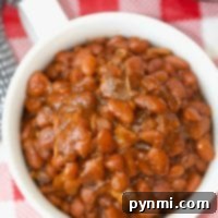 Speedy Instant Pot Baked Beans 3 A bowl of no soak Instant Pot baked beans rests on a red and white checkered tablecloth.