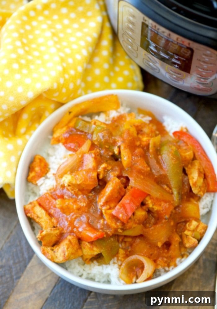 Instant Pot chicken cacciatore is an easy, low-carb dinner idea. Moist, flavorful, and quick to cook, served over rice for a family-favorite meal. A bowl of rice topped with a vibrant Instant Pot chicken cacciatore, featuring tender chicken, colorful bell peppers, and onions, on a yellow polka dot cloth.