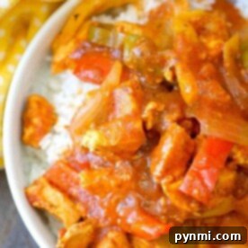 A bowl of chicken cacciatore with bell peppers and onions over white rice, reminiscent of an instant pot chicken cacciatore recipe, sits next to a yellow polka dot cloth.