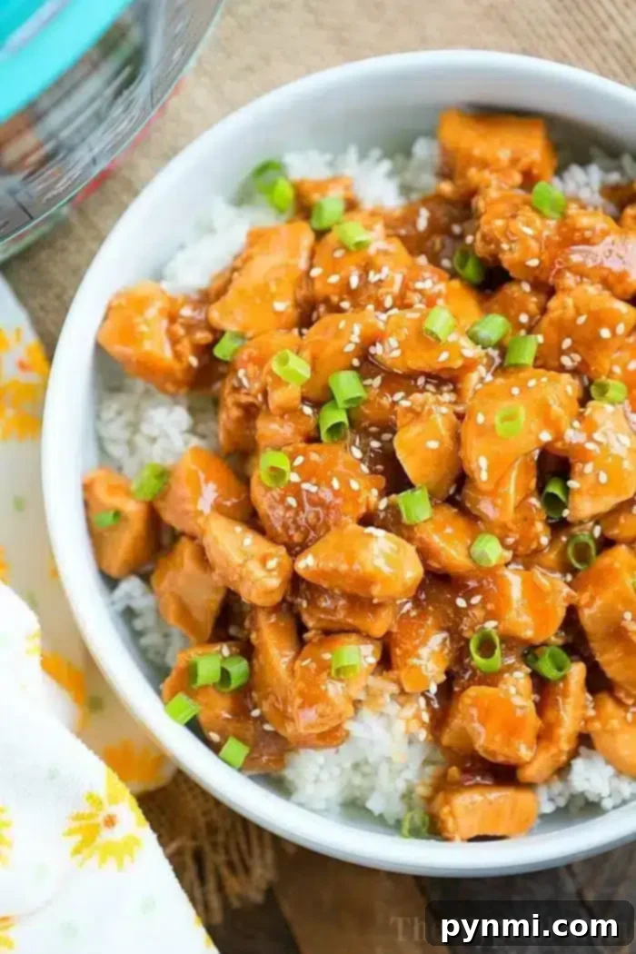 Bowl of white rice topped with tender sesame chicken, green onions, and sesame seeds, crafted from easy instant pot chicken recipes.