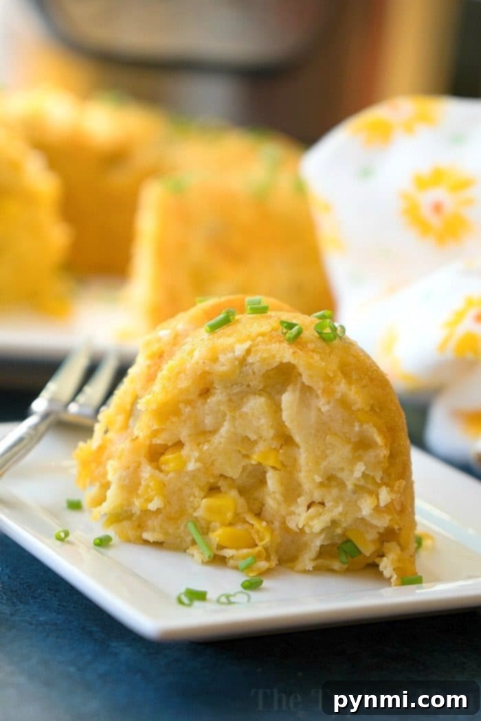 A slice of savory corn pudding with chives graces a square plate, reminiscent of a classic instant pot corn casserole recipe, served with a fork on the side.