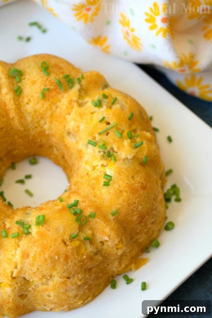 Cheesy corn casserole topped with chopped chives rests temptingly on a white plate, much like an instant pot corn casserole ready to delight your taste buds.