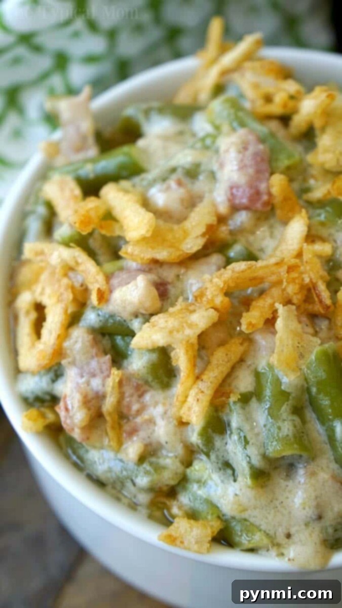 Ninja Foodi Green Bean Casserole with Bacon - Loaded with Flavor and Crispy Onions! Close-up of an instant pot green bean casserole, topped with crispy fried onions, served in a white bowl.