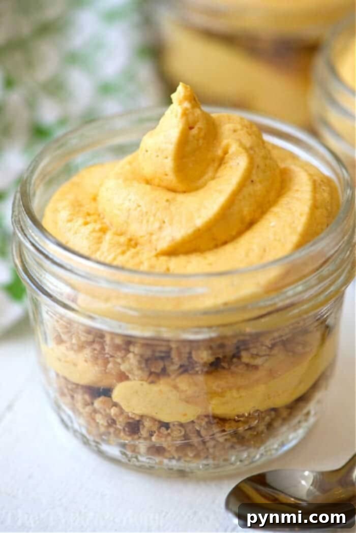 No bake pumpkin cheesecake! #nobake #pumpkin #cheesecake A glass jar with layers of crumbled crust and creamy pumpkin mousse, topped with a swirl of mousse—this No Bake Pumpkin Cheesecake in Jars is the perfect easy, festive treat.