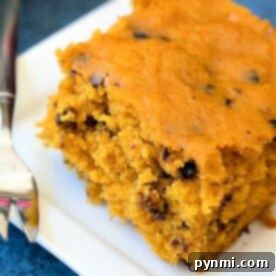 A slice of crockpot pumpkin bread cake with chocolate chips rests invitingly on a white plate.