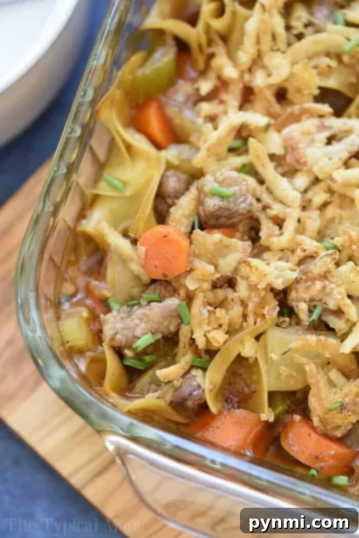 Easy beef stew casserole with carrots, celery, and crispy fried onions in a glass baking dish, ready to be served.