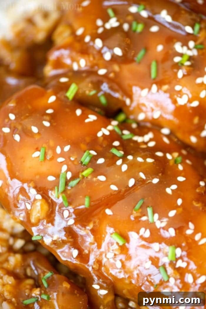 This easy crockpot sticky teriyaki chicken with a kick of heat recipe is amazing and a healthy meal too! Sweet with just a pinch of Sriracha makes it great! Close-up of shredded crockpot sticky teriyaki chicken, glistening with sauce and ready to be served, highlighting its tender texture.