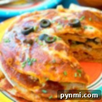 A cheesy Mexican pizza slice, reminiscent of an instant pot Mexican pizza, topped with olives and herbs on a colorful plate.