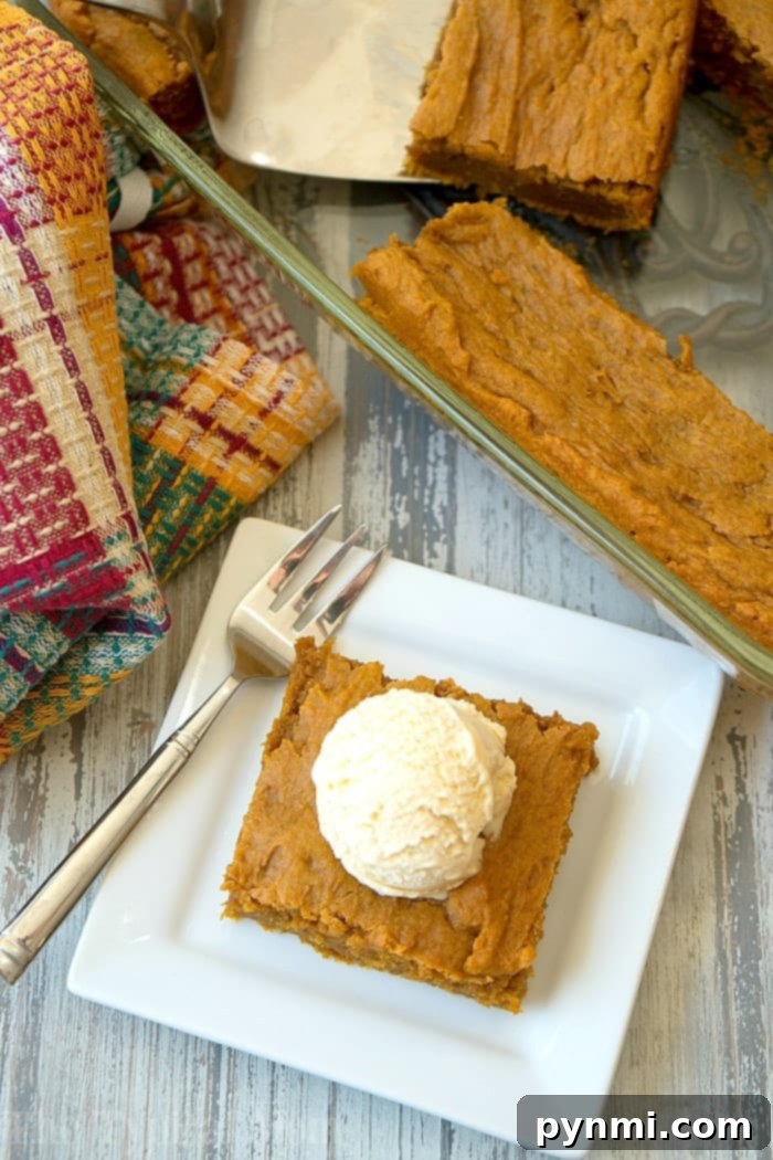Decadent Cake Mix Pumpkin Pudding Delight 4 Three slices of the moist pumpkin pudding cake are artfully arranged on a white serving plate, each glistening with a scoop of vanilla ice cream. The warm, inviting glow of the dessert is evident.