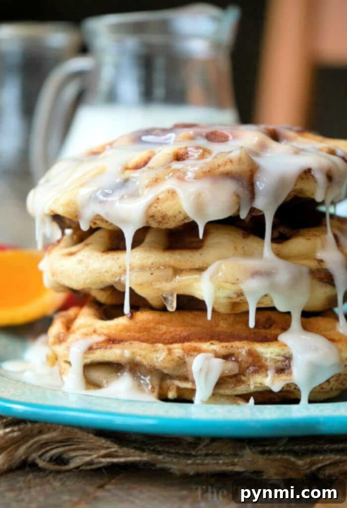 Two perfectly cooked cinnamon roll waffles, one plain and one stuffed with apple pie, on a plate, showcasing the versatility of this easy recipe.