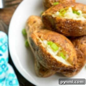 Ninja Foodi baked potatoes split open and topped with chopped green onions on a white plate.