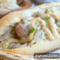 A close-up of an instant pot brat nestled in a bun, topped with mustard, sauerkraut, and chives.