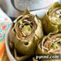 Perfectly Steamed Instant Pot Artichokes 3 Steamed artichokes with Parmesan and green onions sit in a white bowl, freshly cooked to perfection using the Instant Pot.