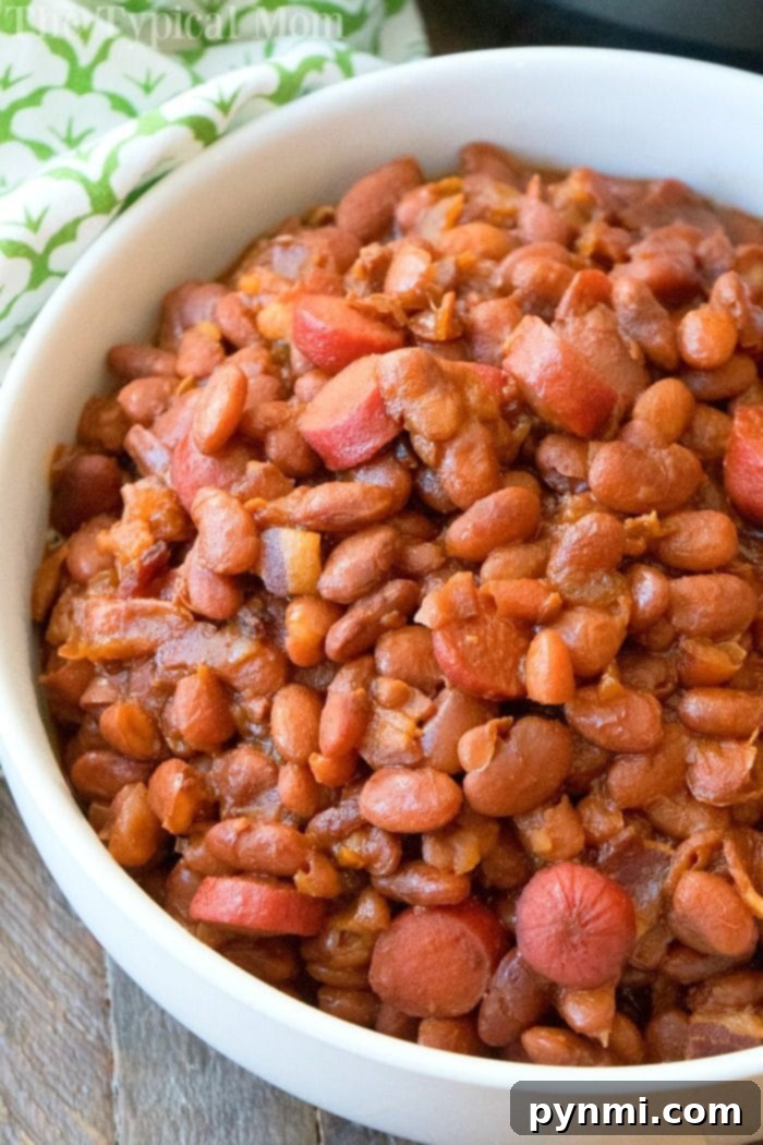 Bowl of homemade Instant Pot Beans and Franks, with a spoon revealing the rich sauce and bean texture