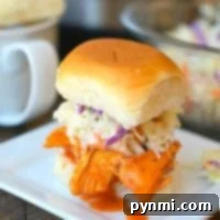 Pulled chicken sliders with coleslaw rest on a square white plate, accompanied by a mug.