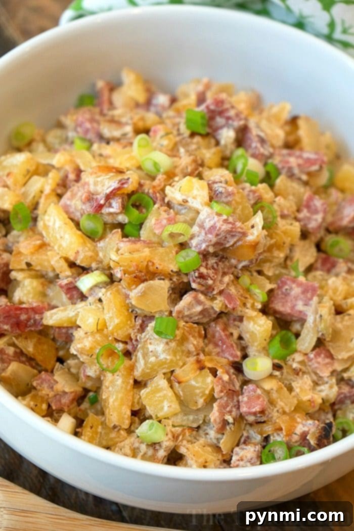 Homemade corned beef hash recipe! The traditional way which is a great hearty breakfast as well as a creamy corned beef hash that my family loves! It's a great way to use leftover corned beef after St. Patricks Day or any time of year. #cornedbeef #cornedbeefhash #homemade #stpatricksday #traditional A bowl of creamy classic corned beef hash, topped with chopped green onions.