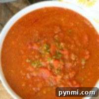 A bowl of hearty spaghetti sauce garnished with herbs sits next to an Instant Pot, ready to whip up a delicious spaghetti sauce, all on a rustic wooden surface.