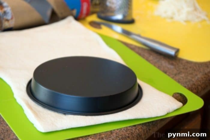 Shaping the Dough for Instant Pot Deep Dish Pizza Pizza dough being pressed into an Instant Pot pizza pan, forming the base and crust of a deep dish pizza.