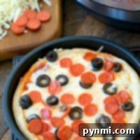 Deep-dish Instant Pot pizza with savory pepperoni and olives, served fresh from the pressure cooker next to a bowl of shredded cheese.
