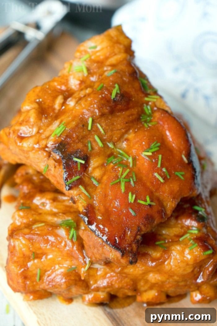 Fall-Off-The-Bone Express Ribs 2 Two pieces of Crock-Pot Express ribs. Glazed and juicy, with a fork and cloth napkin partially visible in the background.