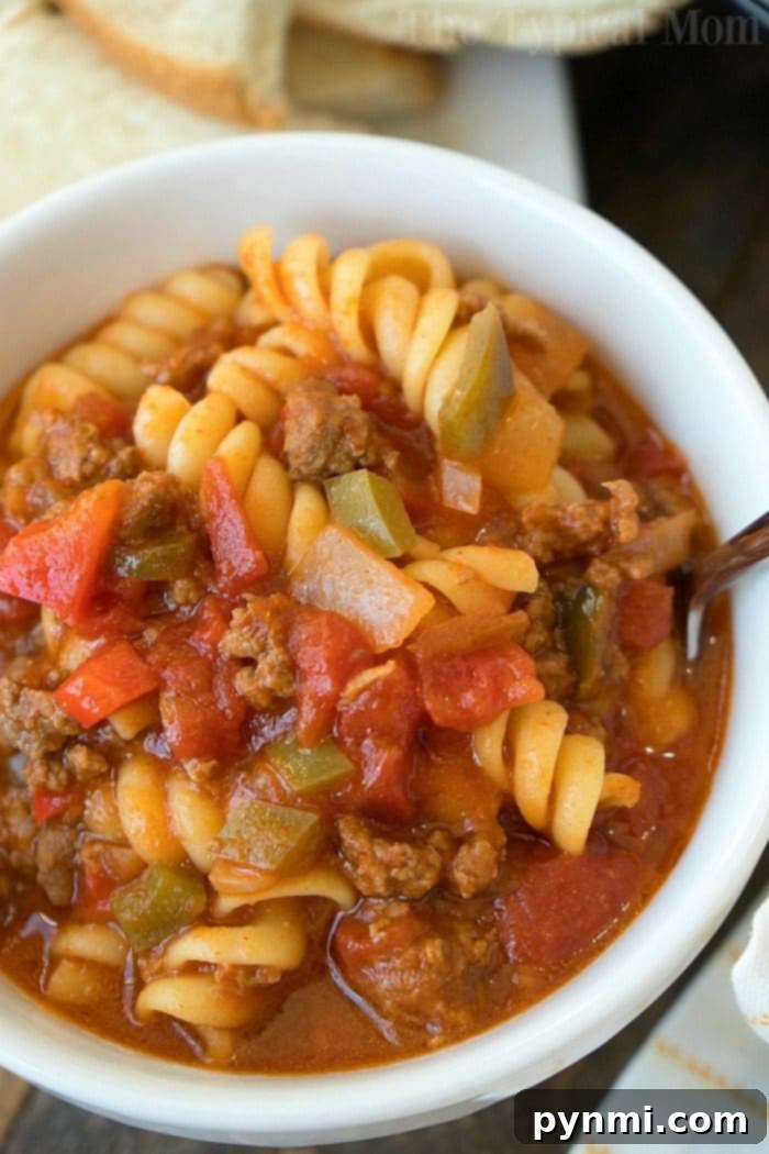 A comforting bowl of Instant Pot Sloppy Joe Casserole, generously garnished with melted cheese and fresh parsley, highlighting a quick, easy, and satisfying family dinner idea cooked in a pressure cooker. #sloppyjoes #casserole #instantpot #pressurecooker #groundbeef #instantpotrecipes #thetypicalmom Large serving of Instant Pot Sloppy Joe Casserole in a bowl, topped with shredded cheddar cheese and a sprinkle of fresh parsley, ready to eat, with a pressure cooker and ingredients in the background.