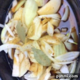 Sliced onions, and bay leaves meld into a savory broth mixture for an easy crockpot French onion soup delight.