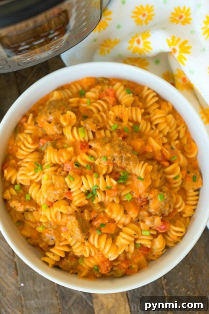 Cheesy Instant Pot goulash turned out amazing in my pressure cooker! Creamy goulash with the same flavors you love with two different cheeses within it too. Total comfort food in your pressure cooker that will be your kid's new favorite dinner for sure. #instantpot #pressurecooker #goulash #cheese #cheesy #pasta #casserole #instantpotrecipes #thetypicalmom A generous serving of creamy, cheesy Instant Pot goulash in a bowl, featuring twisted rotini pasta, ground meat, and a rich tomato sauce, garnished with fresh herbs.