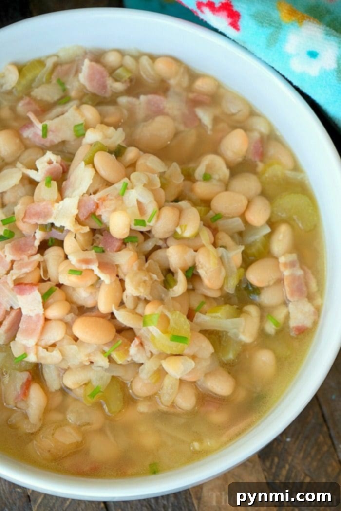 A delicious bowl of pressure cooker white bean soup, garnished with savory bacon and fresh green onions, topped with delicate chives.