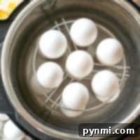 White eggs neatly arranged on a metal rack inside an Instant Pot, the perfect setup for making hard-boiled eggs effortlessly.