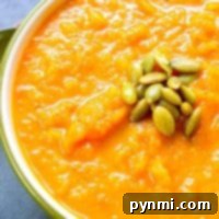 A vibrant bowl of creamy, dairy-free butternut squash soup, garnished with green pumpkin seeds, capturing its rich and inviting texture.