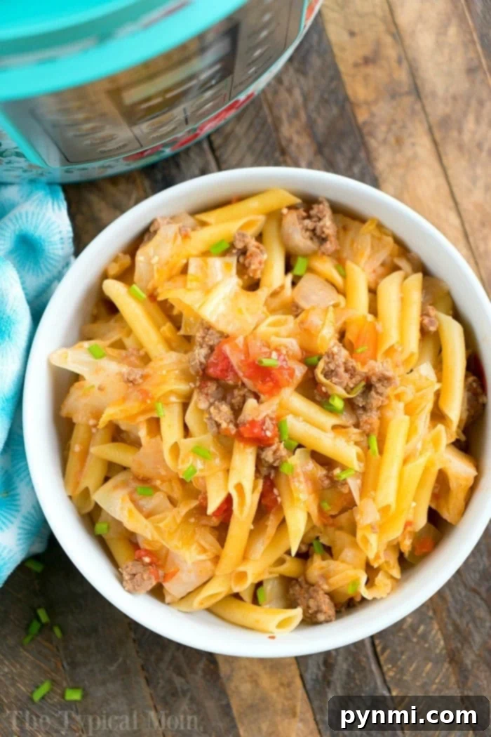 A comforting bowl of Instant Pot sausage and cabbage with noodles, garnished with fresh herbs, served on a wooden table alongside a blue patterned cloth