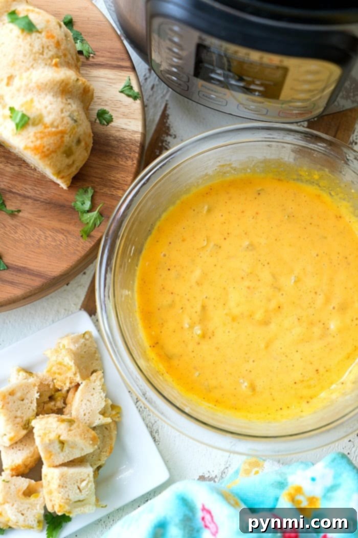 An overhead shot of cheese fondue, ready for dipping with various bread pieces and green vegetables.
