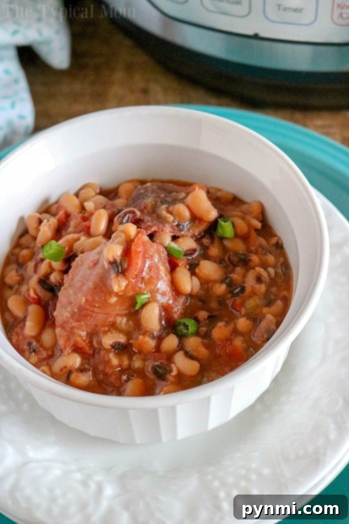 A close-up of a white bowl filled with Black Eyed Peas and Ham, elegantly garnished with fresh herbs, showcasing a rich and flavorful dish.