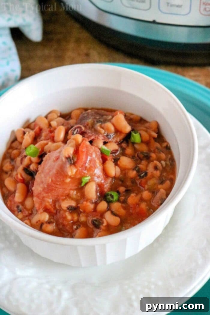 A beautiful white bowl filled with creamy pressure cooker black eyed peas and ham in a savory broth, elegantly garnished with vibrant green onions, ready to be served.