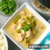 Creamy coconut chicken with a side of rice and fresh herbs nearby, all crafted effortlessly in the pressure cooker.