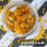 A jar of golden, glittery gummy bears that look like honey slime, with sequins on a black and white striped background.