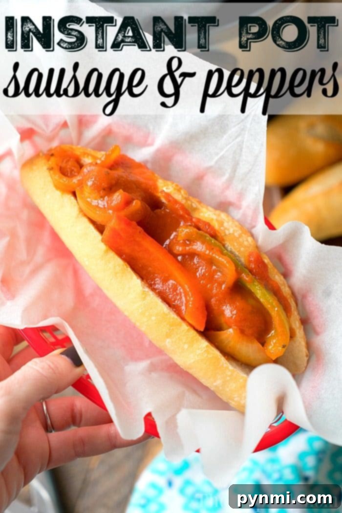 A hand holds a red basket lined with white paper, containing a sub sandwich filled with sausages and red and green bell peppers in a tomato-based sauce. Text at the top of the image reads, "Pressure Cooker Sausage & Peppers.