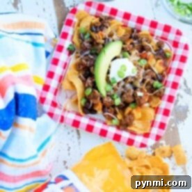 A plate of nachos topped with avocado, sour cream, and green onions sits next to a Fritos bag and colorful napkin, reminiscent of an Instant Pot Frito chili pie recipe.