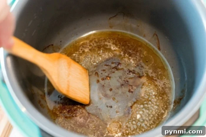 A wooden spatula gently stirs browning butter in a pot, the aroma mingling with the richness of pressure cooker short ribs. The butter bubbles, forming a caramelized layer at the bottom, enhancing the flavors of this delicious dish.