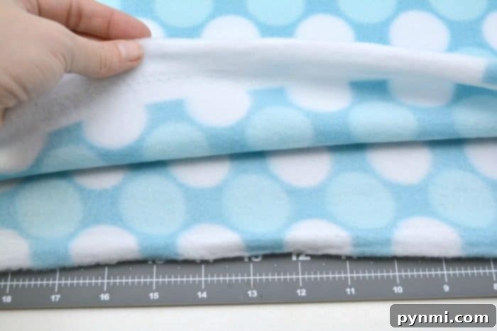 Close-up of fleece fabric being measured and marked with a ruler and pencil for a knot pillow DIY.