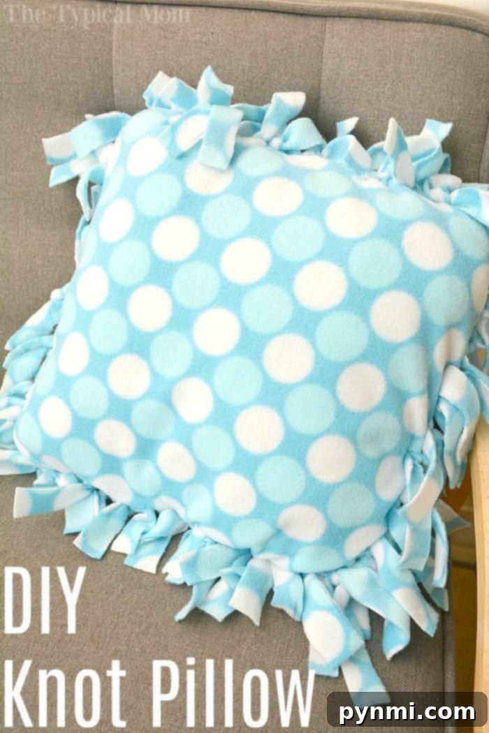 A finished blue polka dot knot pillow resting on a bed, demonstrating the success of the easy DIY craft project.