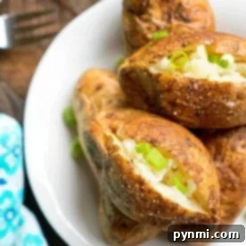 Baked potatoes on a white plate, topped with butter and chopped green onions