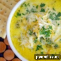 A bowl of Pressure Cooker Broccoli Cheddar Soup topped with shredded cheese and parsley, served with crackers.